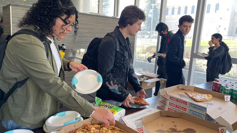 Students get a snack of pizza at buffet