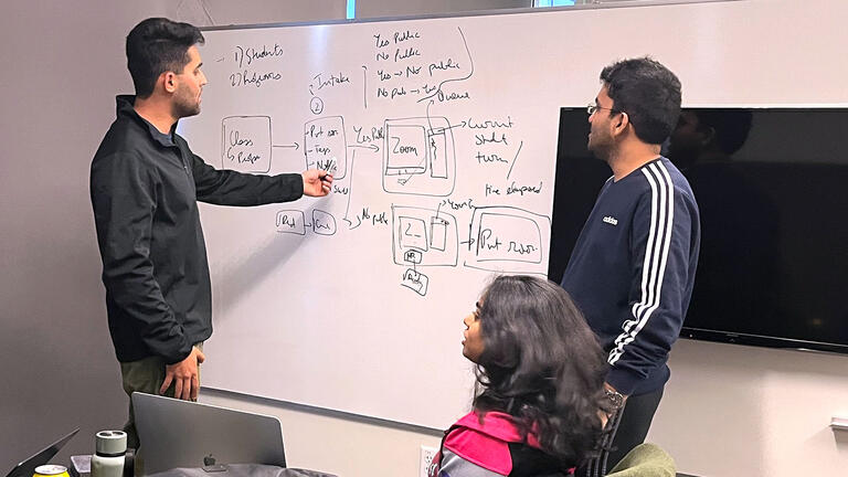 Students work on a white board in a conference room