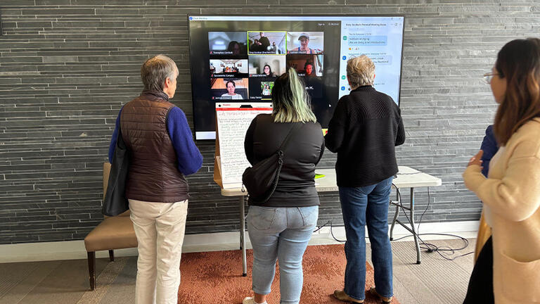 Three people looking at a TV screen