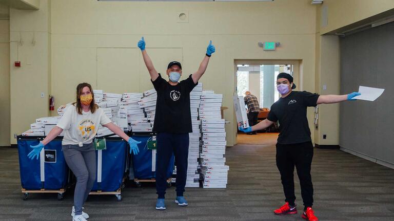 Three volunteers in front of boxes