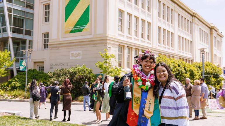 Graduate smiling with a relative in Gleeson Plaza