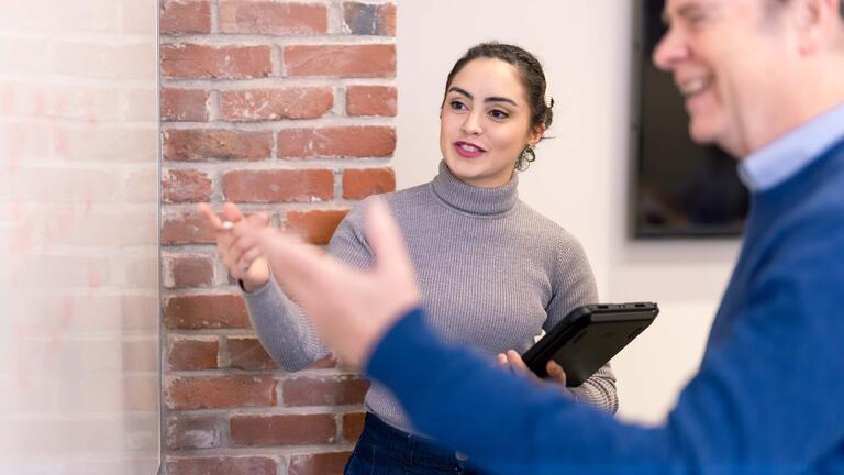 Two people pointing at a board