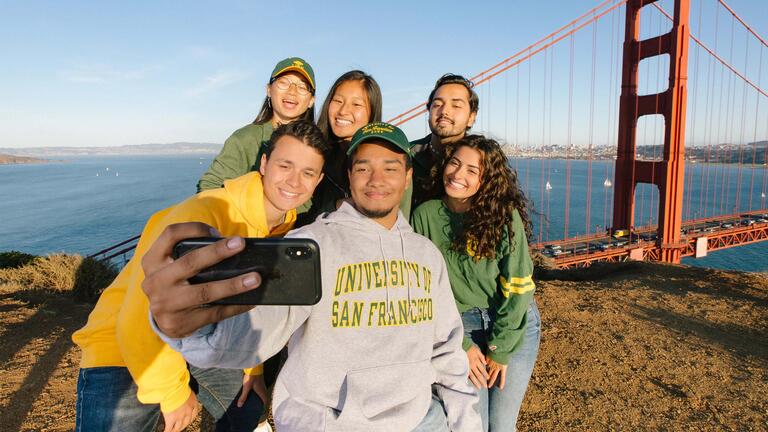 student taking a selfie on a bluff overlooking the golden gate bridge