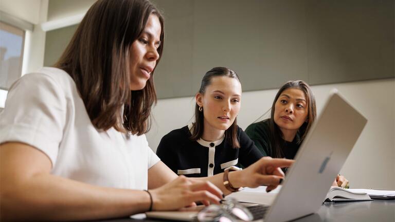 Three students looking at a laptop