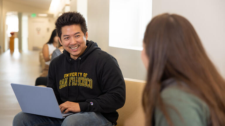 students sits on couch with laptop