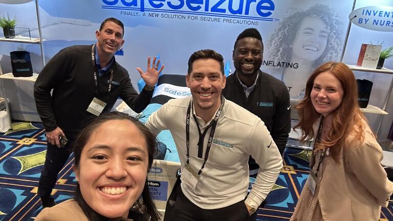 Student taking a picture with other people in front of a sign that says "SafeSeizure"