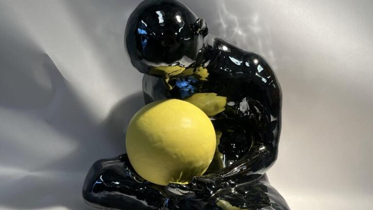 Ceramic human figure in lotus holding a yellow sphere