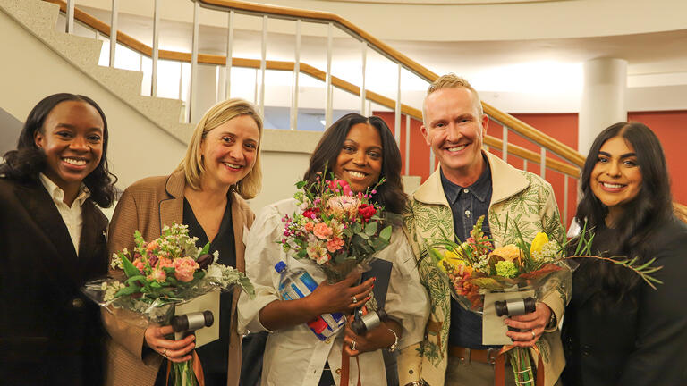 group of people holding flowers and smiling at event