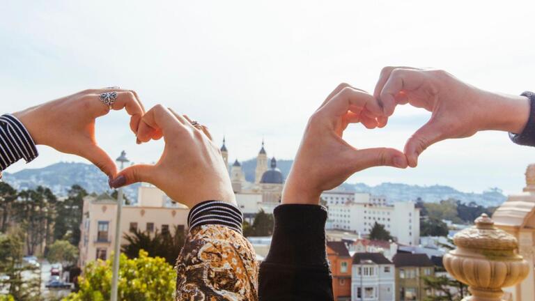 Two students put up heart hand signs in front of the church