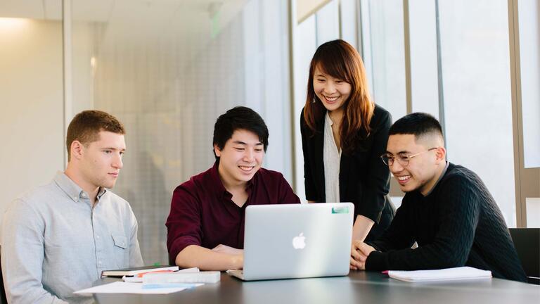 Four students looking at a laptop