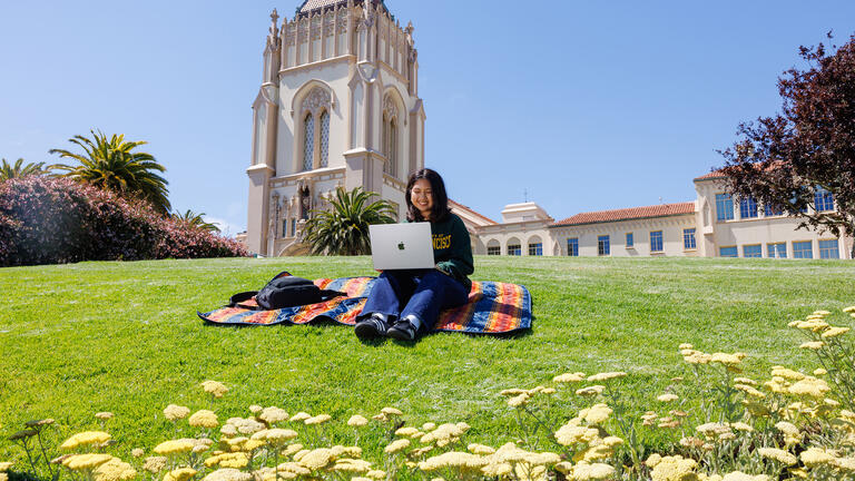 student uses laptop on lawn