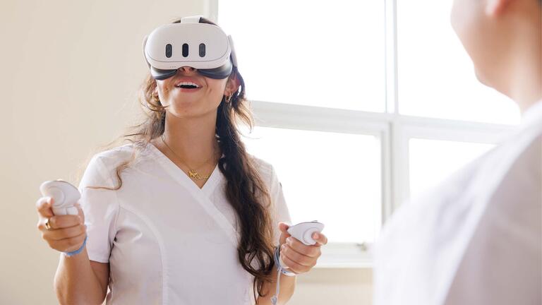 Nursing student wearing scrubs putting on a VR headset
