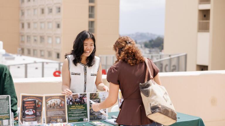 Student speaking with a representative at a tabling event.
