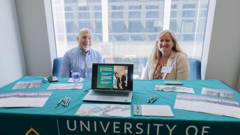 2 representatives sitting at a table during a tabling event.