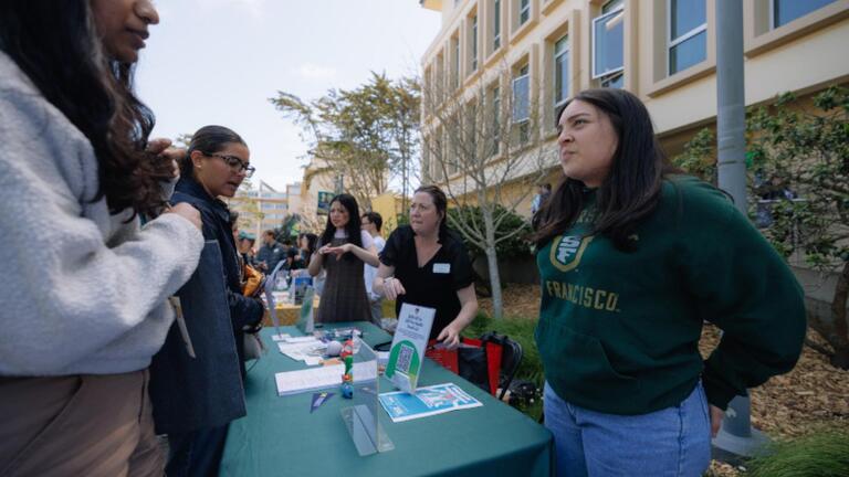 Students speaking with representataives at a tabling event