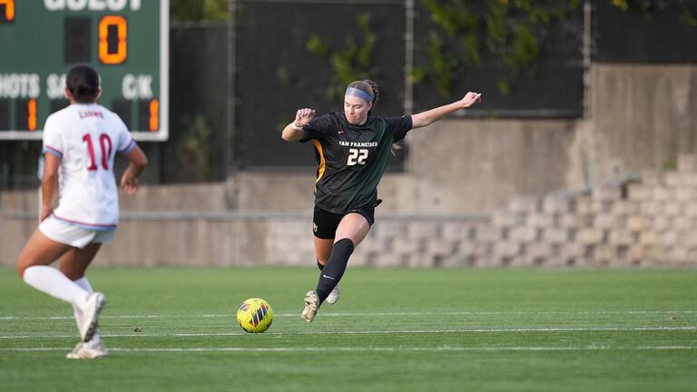 student kicks soccer ball