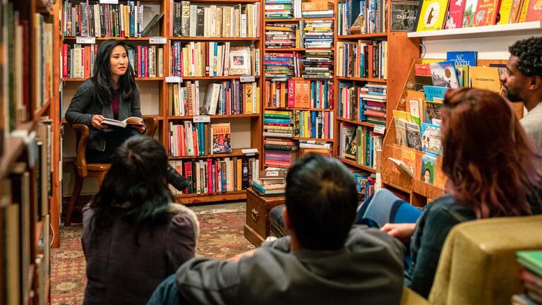 person reads reads a book to audience in a bookstore