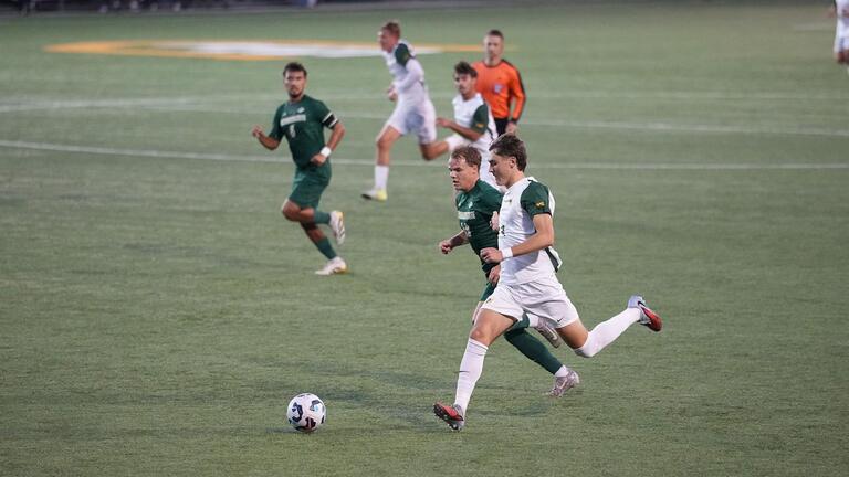 soccer players run after ball during game