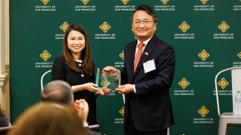 Two people standing and accepting a recognition award