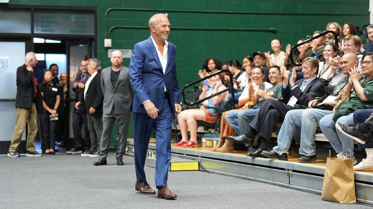 Kevin Costner walks in front of audience members at the Silk Speaker Series