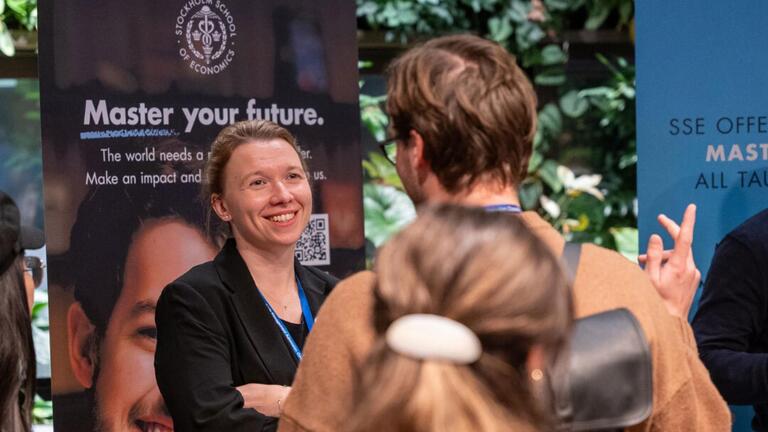 People talking at a USF Masters tour table