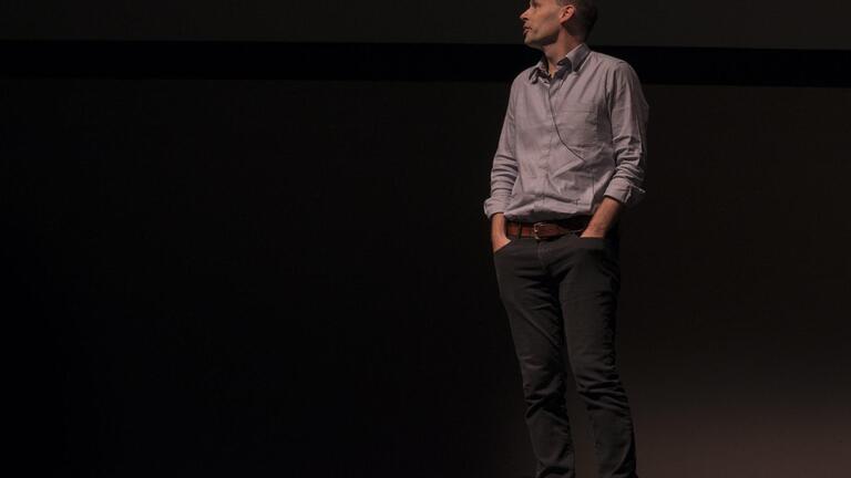Aaron Straup in a button-up speaking on stage.