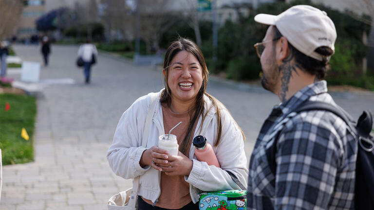 Two graduate students chatting, smiling in front of Gleeson Library