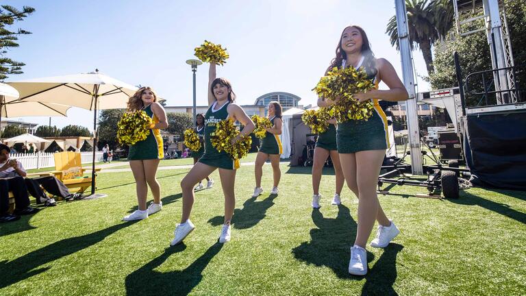 USF cheerleaders on campus cheering, waving pom-poms