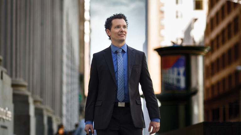 Business person walking down city street in suit and holding briefcase