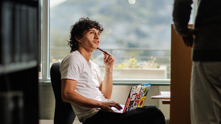 student sits in library with laptop on lap