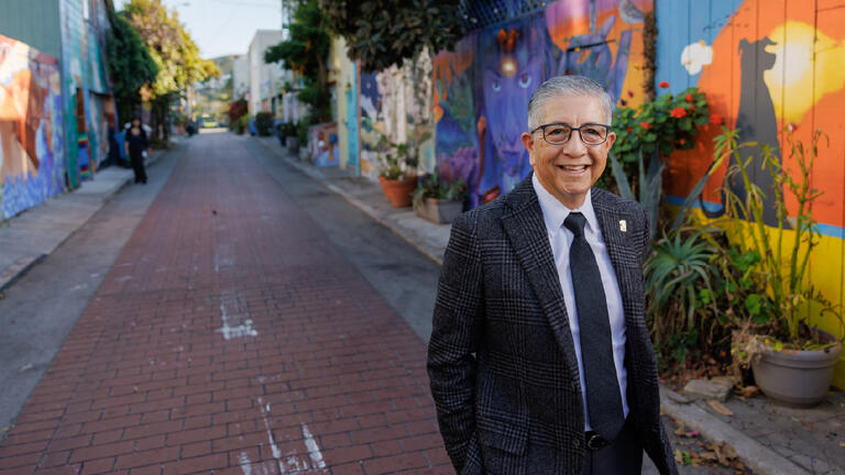 President Aceves walking in a mural filled alley in the mission