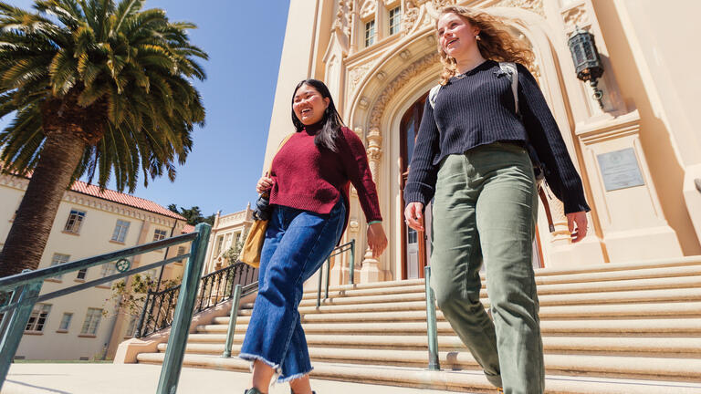 two students walking down stairs outside