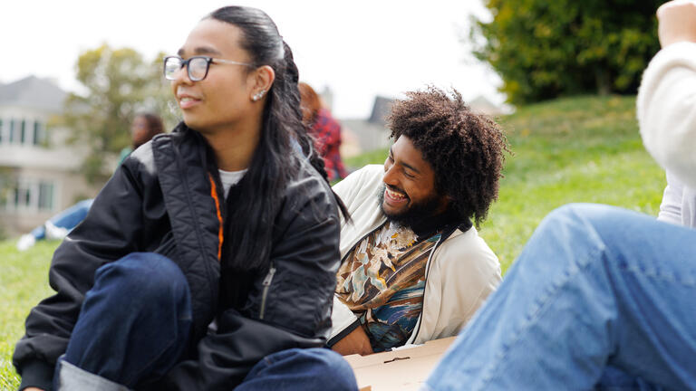 students laying in grass together on usf campus
