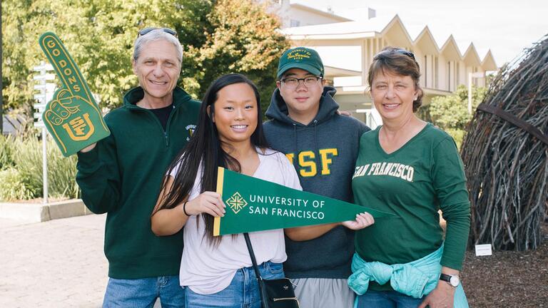 Family members with a student hold USF banners and foam fingers.