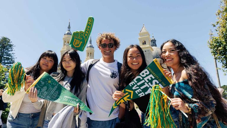 USF students smiling and holding up spirit swag 