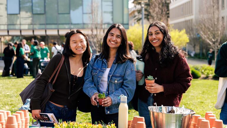 Group of three students smiling at the succulent planting station during Day of the Dons, stress less activity