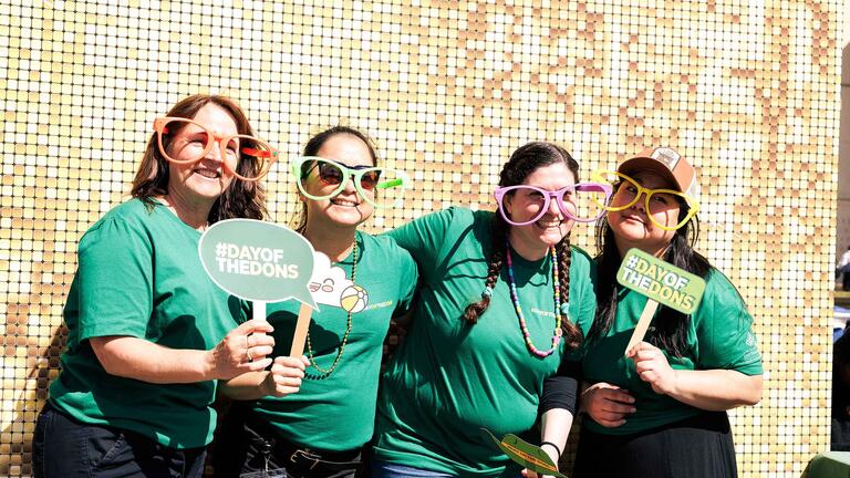 Group of four at posing at the Day of the Dons photo booth with props