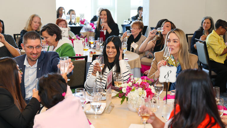Table of guests at the WILP Symposium cheersing during the champagne toast