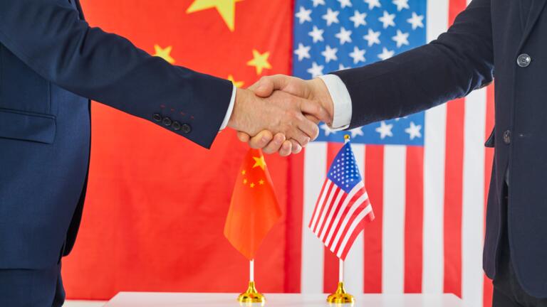 Handshake in front of Chinese and American flags