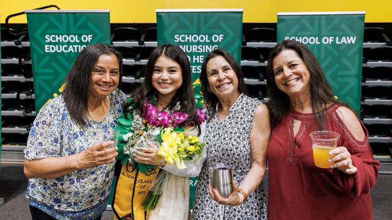 family stands with graduating student