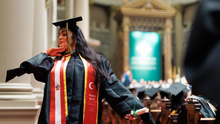 student happily poses inside st.ignatius church during her commencement ceremony