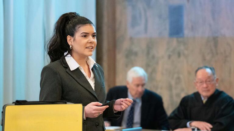 Student in suit presents in a courtroom