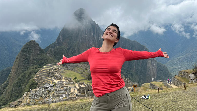 student stands atop andes mountains