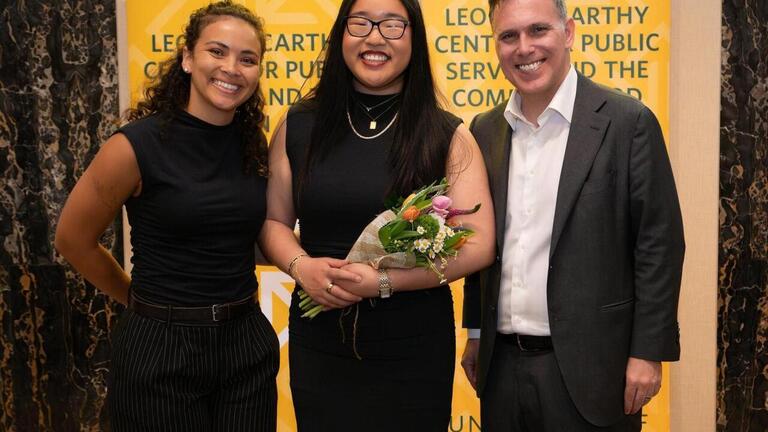 Three people in front of yellow banner