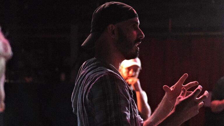 Eric Garcia in rehearsal shown with a side profile in a dimly lit room
