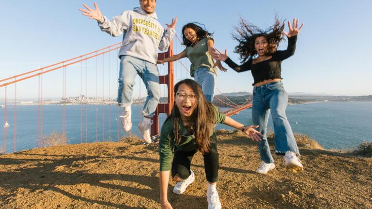 Four students with excitement with Golden Gate Bridge in the background.