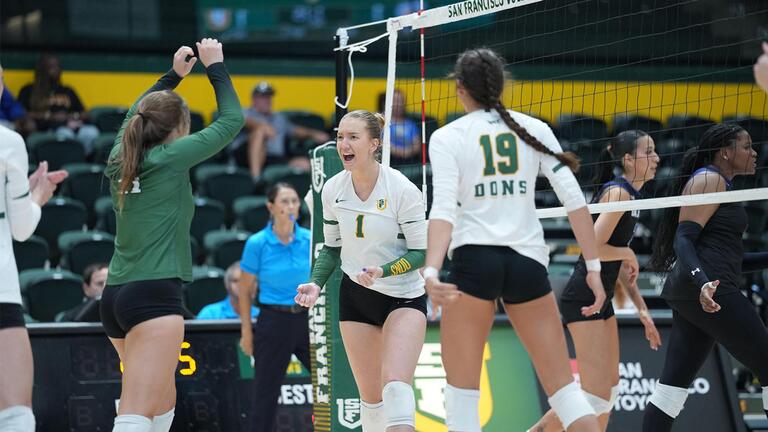 Womens volleyball players on court cheering each other on