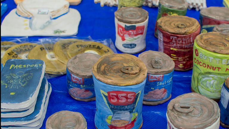 Ceramic canned foods next to ceramic passports on a blue table