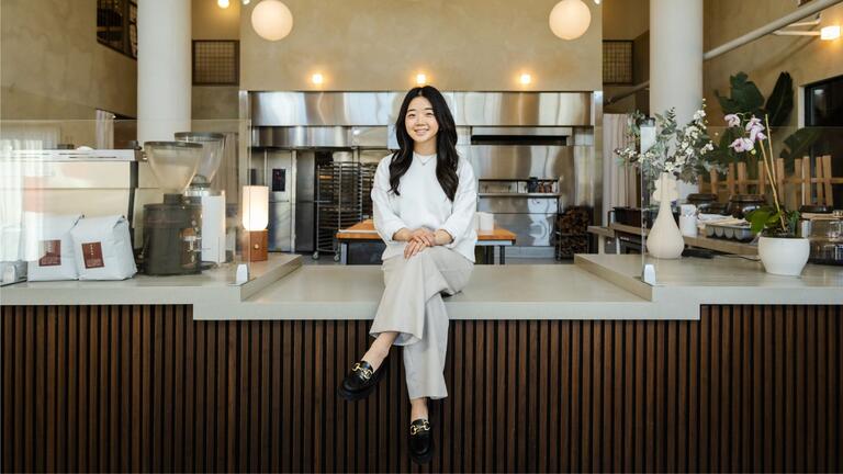 Janet Lee ’15, co-founder of Sōhn sitting on the counter of the coffee bar.