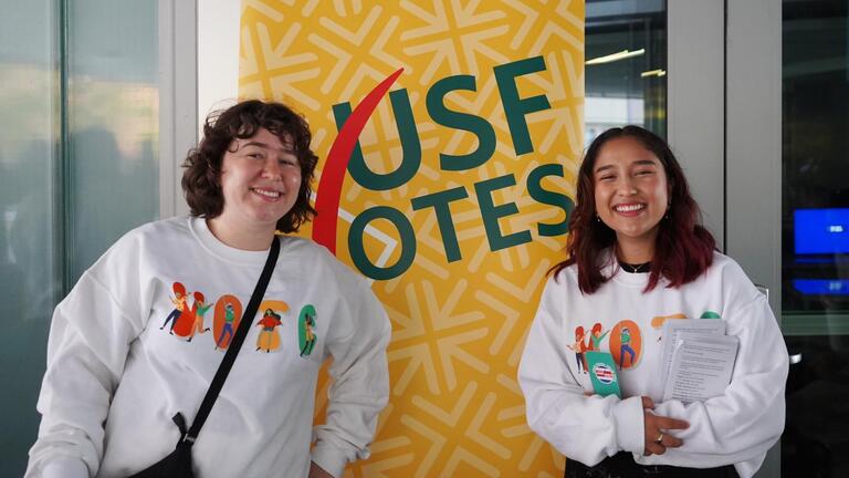 students stand in front of sign that says USFVotes